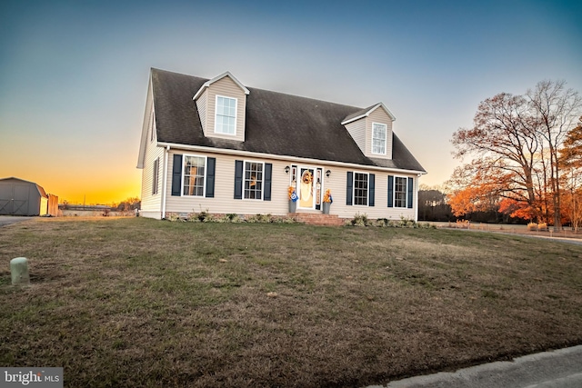 cape cod house with a lawn and an outbuilding