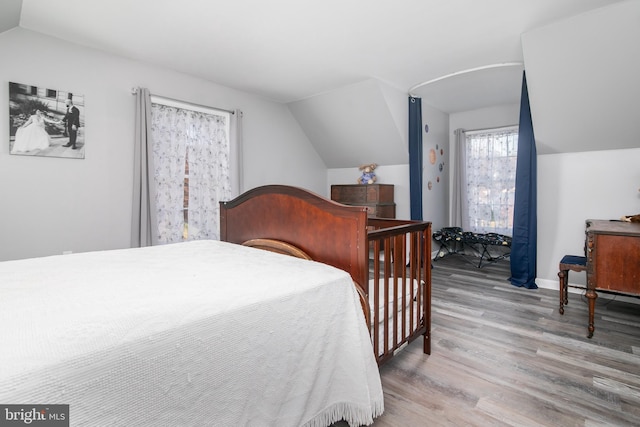 bedroom with light wood-type flooring and vaulted ceiling