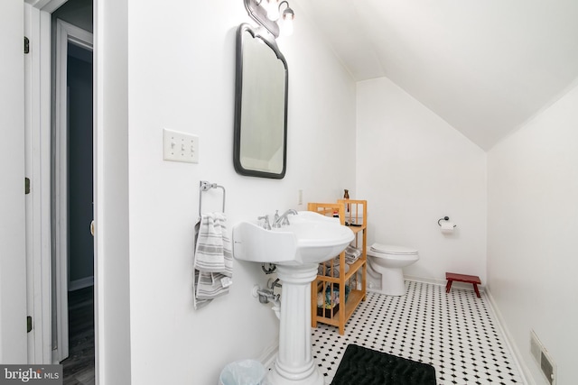 bathroom featuring toilet, lofted ceiling, and sink