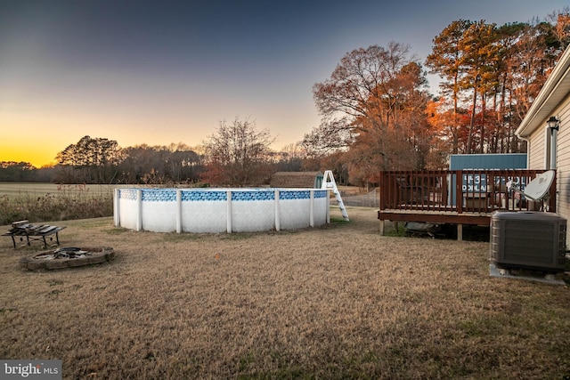 yard at dusk with central AC and a pool side deck