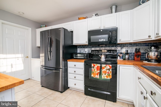 kitchen featuring black appliances, white cabinets, decorative backsplash, light tile patterned flooring, and butcher block counters