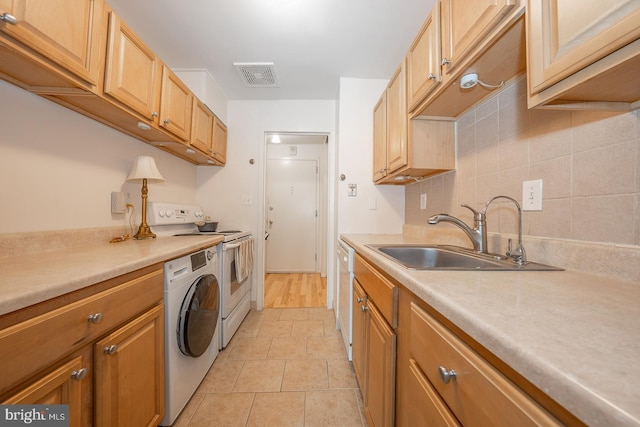 kitchen with white dishwasher, electric stove, washer and dryer, sink, and light tile patterned flooring