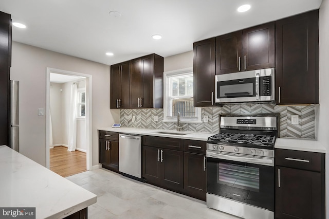 kitchen with sink, decorative backsplash, appliances with stainless steel finishes, light tile patterned flooring, and dark brown cabinetry