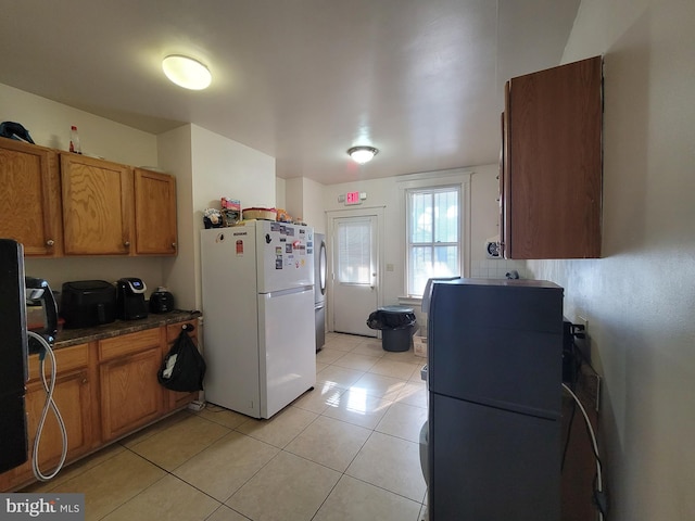 kitchen with white refrigerator, black fridge, and light tile patterned flooring