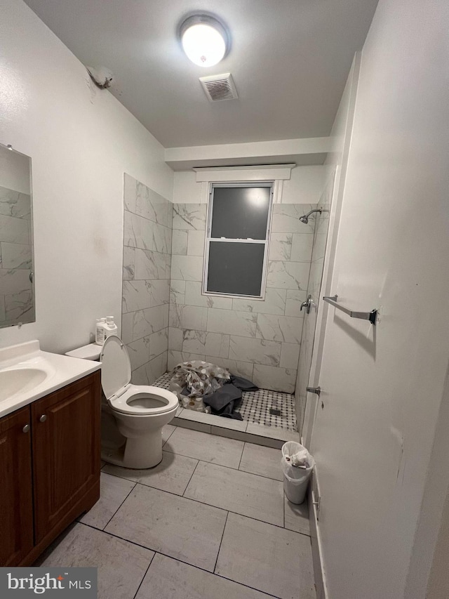 bathroom featuring tile patterned floors, vanity, toilet, and tiled shower