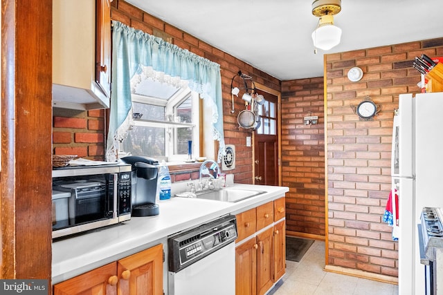 kitchen with dishwashing machine, white fridge, brick wall, and sink