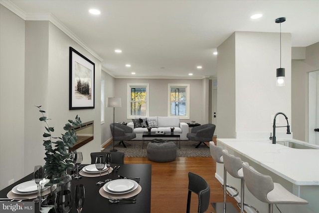 living room featuring hardwood / wood-style flooring, ornamental molding, and sink