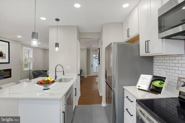 kitchen featuring hanging light fixtures, sink, appliances with stainless steel finishes, light stone counters, and white cabinetry