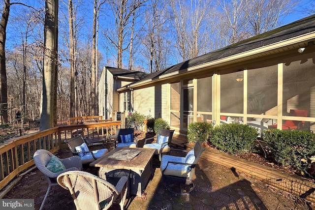 wooden terrace with a sunroom and an outdoor fire pit