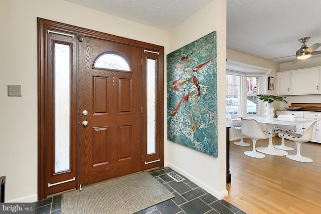 foyer entrance featuring a textured ceiling, ceiling fan, a healthy amount of sunlight, and dark wood-type flooring