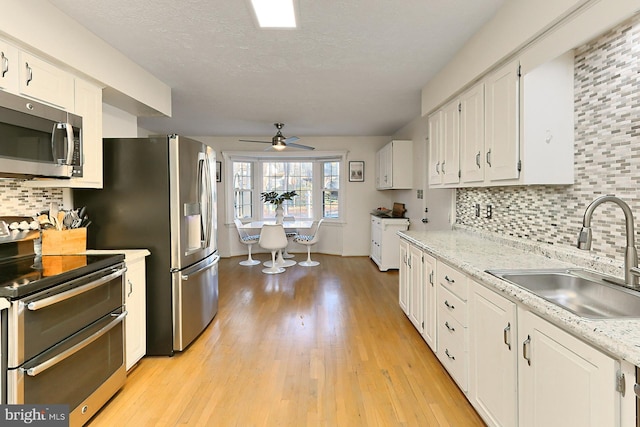 kitchen featuring white cabinetry, sink, light hardwood / wood-style floors, and appliances with stainless steel finishes