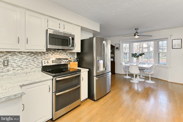 kitchen with decorative backsplash, stainless steel appliances, ceiling fan, light hardwood / wood-style flooring, and white cabinetry