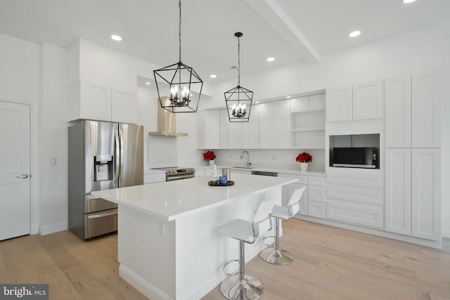 kitchen featuring appliances with stainless steel finishes, sink, white cabinets, a center island, and light hardwood / wood-style floors