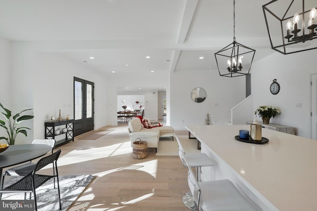 dining room with beam ceiling, french doors, a chandelier, and light wood-type flooring