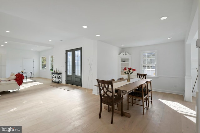 dining area featuring french doors, light wood-type flooring, and a healthy amount of sunlight