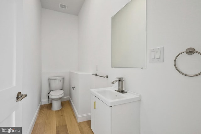 bathroom with hardwood / wood-style floors, vanity, and toilet