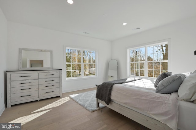 bedroom featuring multiple windows and light hardwood / wood-style flooring