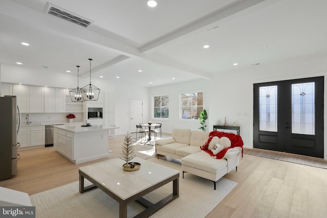 living room with sink, french doors, light wood-type flooring, and beam ceiling