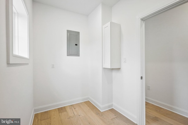 laundry area with electric panel and light wood-type flooring