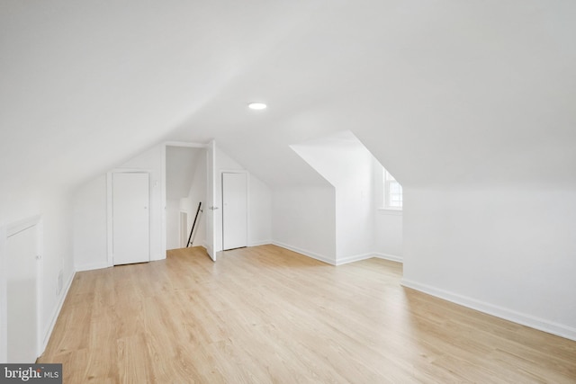 bonus room with vaulted ceiling and light wood-type flooring