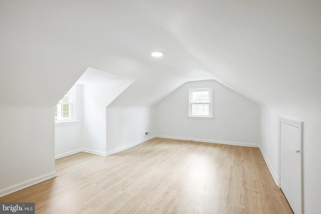 additional living space with light hardwood / wood-style floors and lofted ceiling