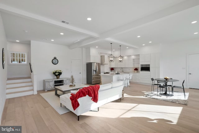 living room featuring beam ceiling, light hardwood / wood-style flooring, and sink