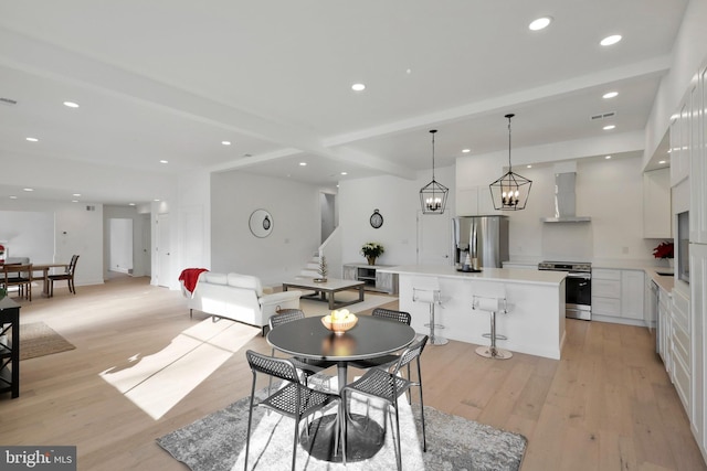 dining space with beamed ceiling, light hardwood / wood-style floors, and a notable chandelier