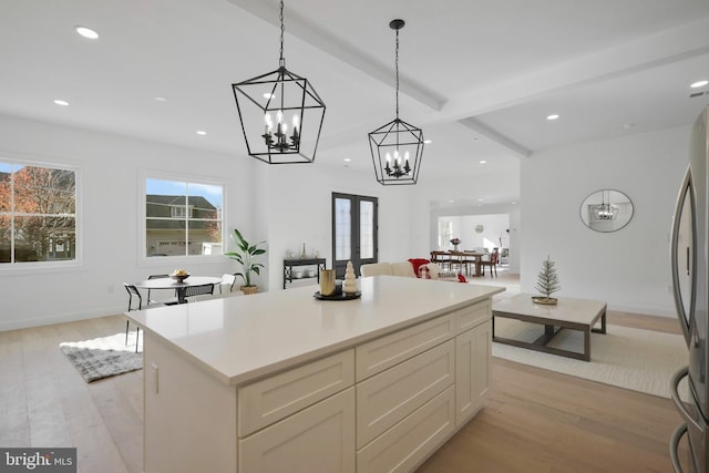 kitchen featuring stainless steel fridge, pendant lighting, light hardwood / wood-style flooring, beamed ceiling, and a kitchen island