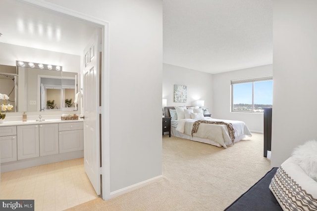 carpeted bedroom featuring ensuite bath and sink