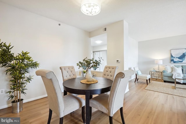 dining space with a chandelier and light hardwood / wood-style floors