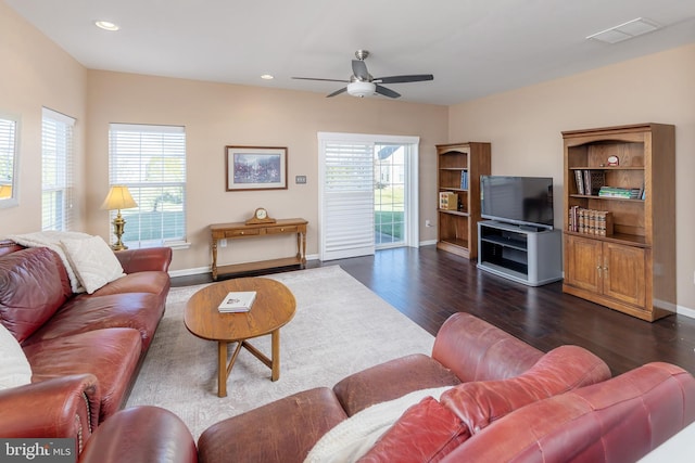 living room with a healthy amount of sunlight, ceiling fan, and dark wood-type flooring