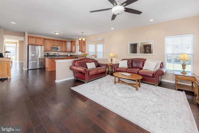 living room with dark wood-type flooring and ceiling fan with notable chandelier