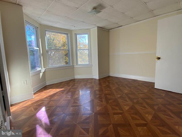 unfurnished room with a paneled ceiling and dark parquet flooring