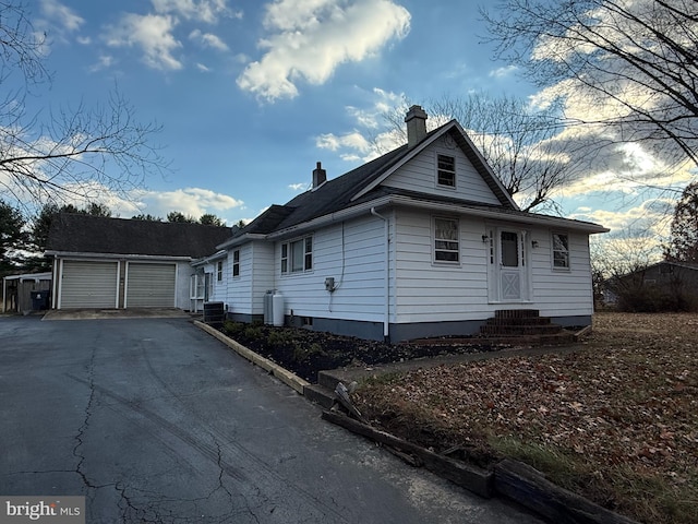 bungalow-style home featuring an outdoor structure, a garage, and central air condition unit