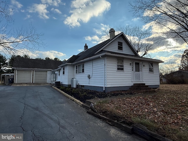 view of front facade featuring a garage, cooling unit, and an outdoor structure