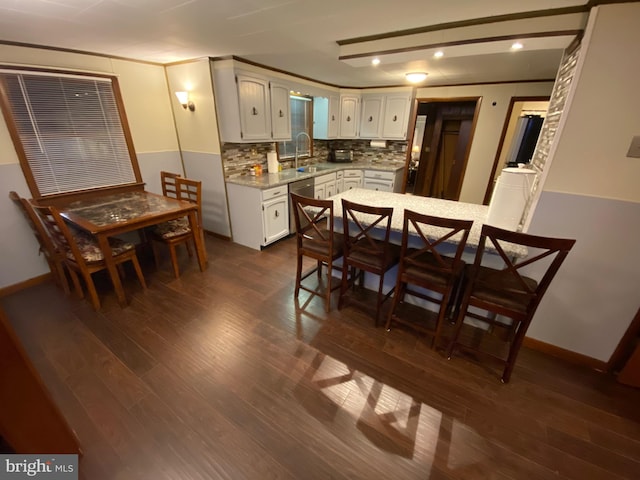 kitchen with white cabinetry, sink, dark wood-type flooring, stainless steel dishwasher, and decorative backsplash