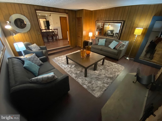 living room featuring wood walls, a textured ceiling, and hardwood / wood-style flooring