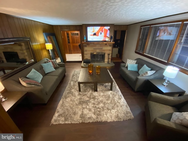 living room with dark hardwood / wood-style floors, wood walls, and a textured ceiling