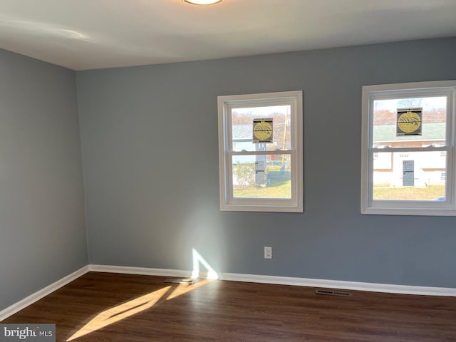 empty room with plenty of natural light and dark hardwood / wood-style flooring