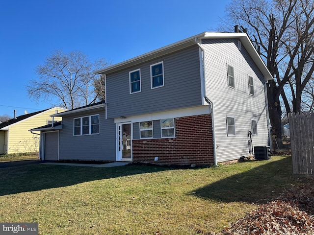 rear view of house with central AC unit and a lawn