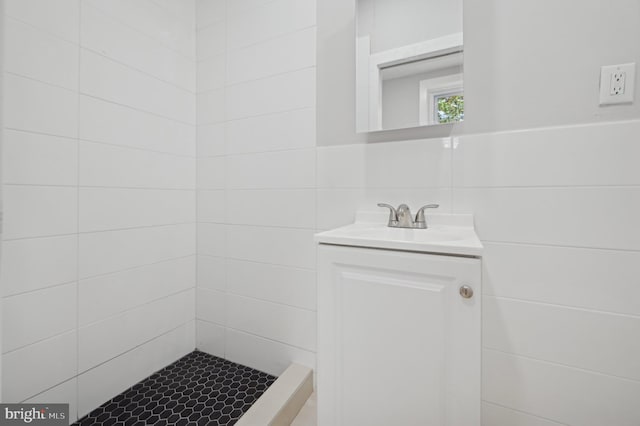 bathroom featuring backsplash, a shower, vanity, and tile walls