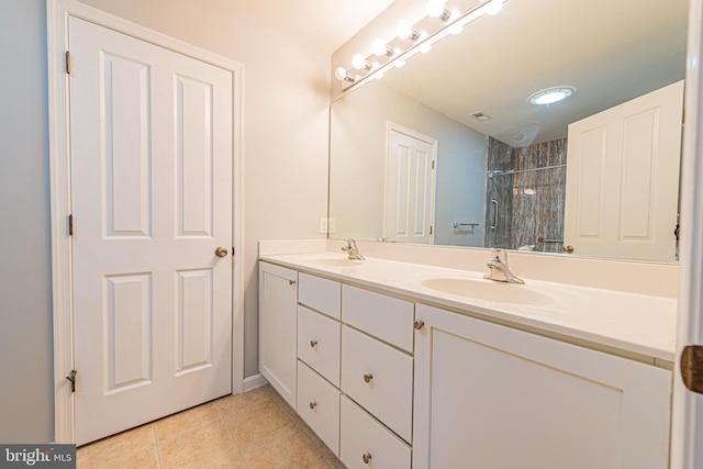 bathroom with a tile shower, vanity, and tile patterned floors