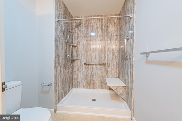 bathroom featuring tiled shower, tile patterned flooring, and toilet