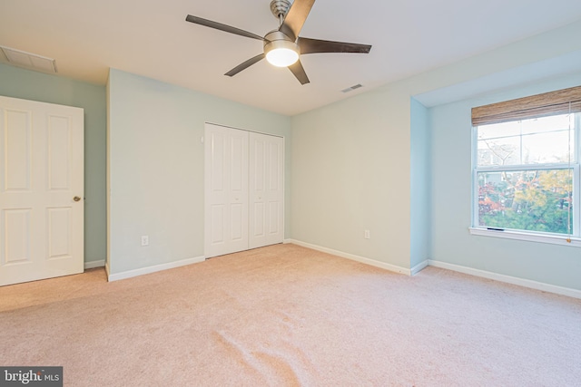 unfurnished bedroom with ceiling fan, light carpet, and a closet