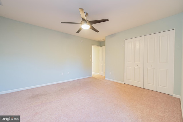 unfurnished bedroom featuring a closet, light colored carpet, and ceiling fan