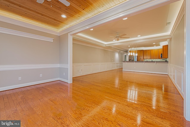 empty room featuring wooden ceiling, a raised ceiling, crown molding, ceiling fan, and light hardwood / wood-style floors