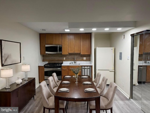 kitchen featuring backsplash, sink, stainless steel appliances, and light hardwood / wood-style floors