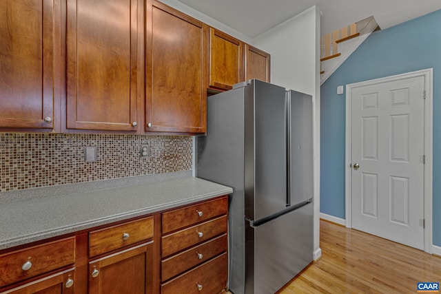 kitchen with tasteful backsplash, stainless steel refrigerator, and light hardwood / wood-style floors