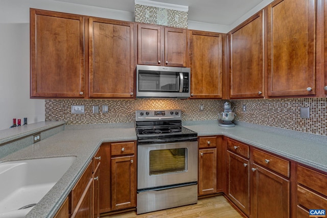 kitchen featuring tasteful backsplash, sink, light hardwood / wood-style flooring, and appliances with stainless steel finishes