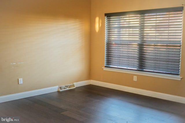 empty room with plenty of natural light and dark wood-type flooring